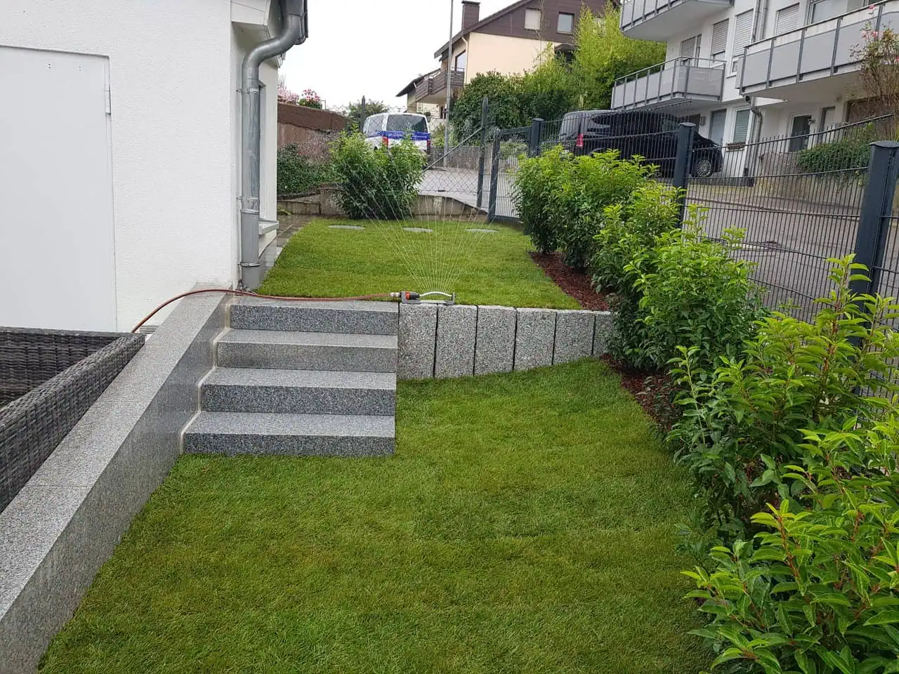 Bewässerung im Garten, grüner Rasen, Steintreppe, Begrenzungsmauer, Gartenpflege in Stuttgart.