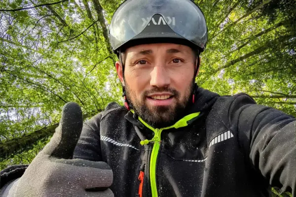 Baumkletterer trägt Helm beim Arbeiten im Baum.